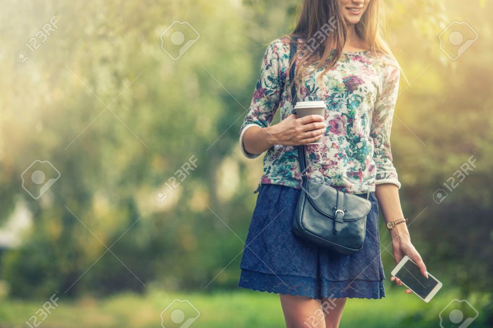 Beautiful woman model with take-away coffee and a telephone in t